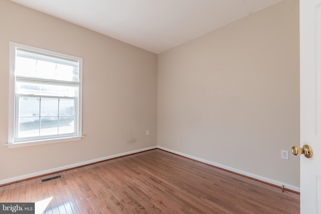 spare room featuring visible vents, baseboards, and wood finished floors