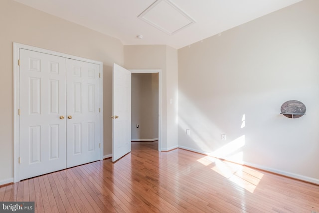 unfurnished bedroom with hardwood / wood-style floors, baseboards, and a closet