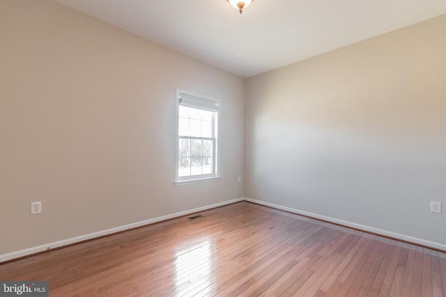 spare room featuring visible vents, wood-type flooring, and baseboards