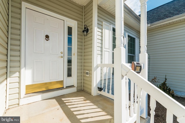 property entrance with covered porch and roof with shingles