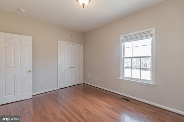 unfurnished bedroom featuring visible vents, baseboards, and hardwood / wood-style flooring