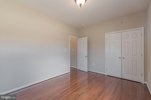 unfurnished bedroom featuring a closet, baseboards, and wood finished floors