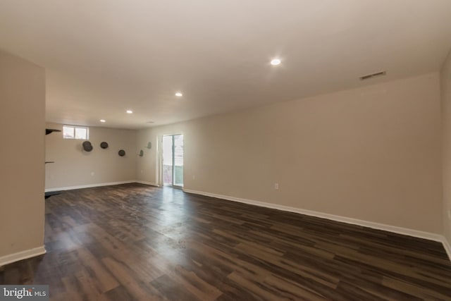 empty room with dark wood finished floors, recessed lighting, visible vents, and baseboards