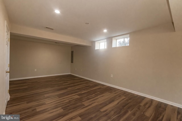 basement with baseboards, visible vents, and dark wood-style flooring