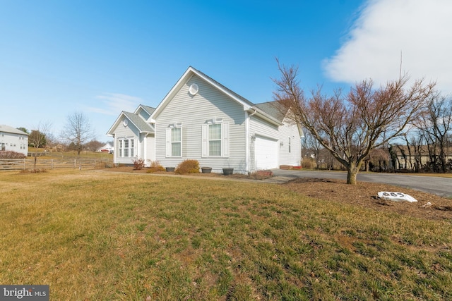 view of front of home featuring aphalt driveway, a garage, a front lawn, and fence