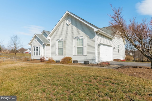 view of home's exterior featuring aphalt driveway, a lawn, a garage, and fence