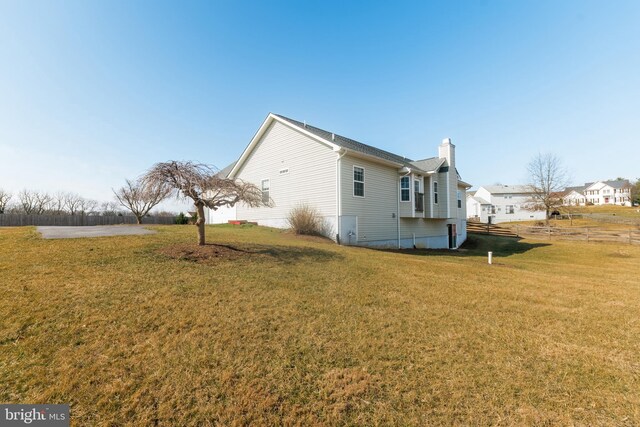 view of side of home featuring a lawn and a chimney