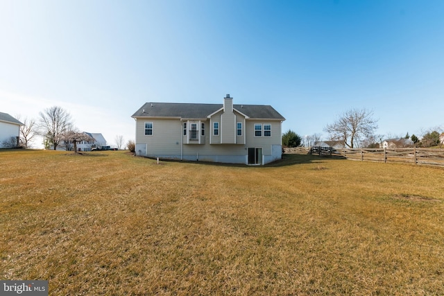 rear view of property with central air condition unit, a chimney, a yard, and fence