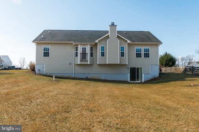 back of house featuring a shingled roof, fence, a lawn, and a chimney