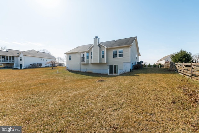 back of property featuring fence, a lawn, and a chimney