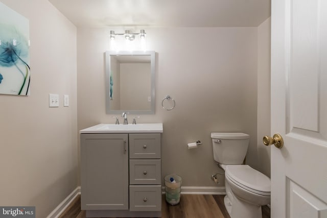 bathroom featuring baseboards, toilet, wood finished floors, and vanity