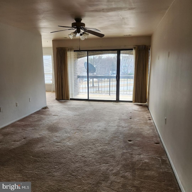 carpeted spare room featuring a ceiling fan and baseboards