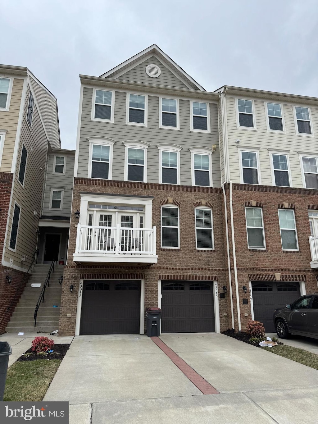 multi unit property with a garage, driveway, and brick siding