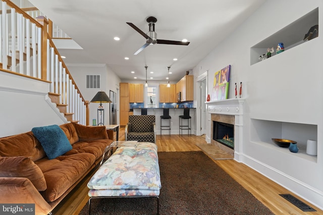 living area with light wood finished floors, visible vents, and a ceiling fan
