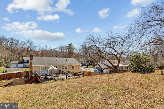 rear view of house featuring a yard, a chimney, a deck, and fence