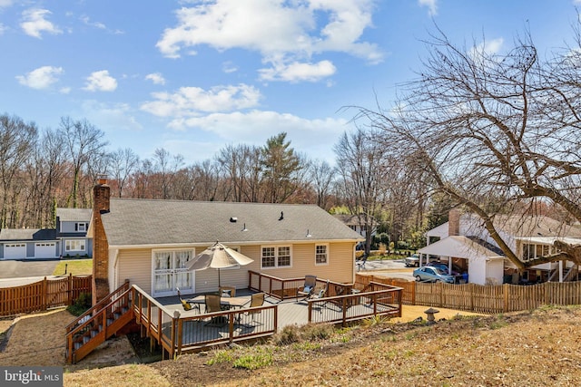 rear view of property featuring a deck, a chimney, and fence