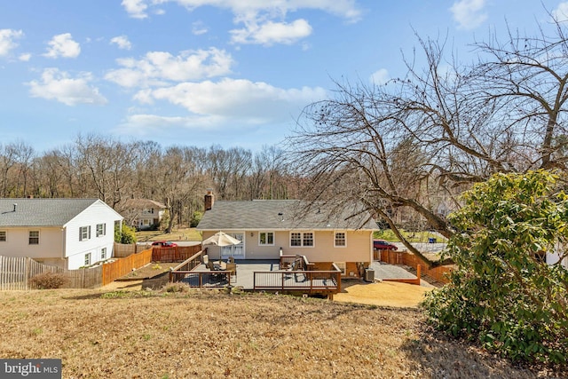 rear view of property featuring a fenced backyard, a chimney, and a deck