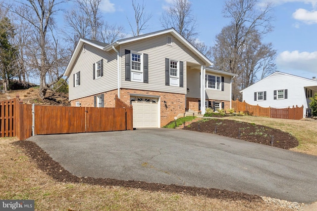 view of front of home featuring a gate, aphalt driveway, fence, an attached garage, and brick siding