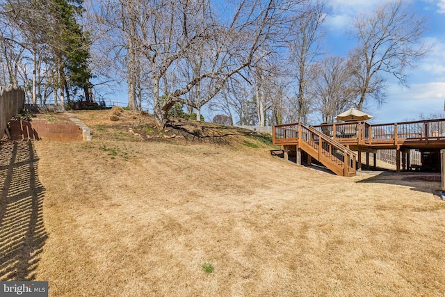 view of yard featuring a deck, stairway, and fence