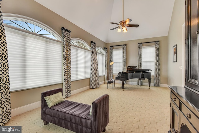 living area with baseboards, lofted ceiling, light colored carpet, and a ceiling fan