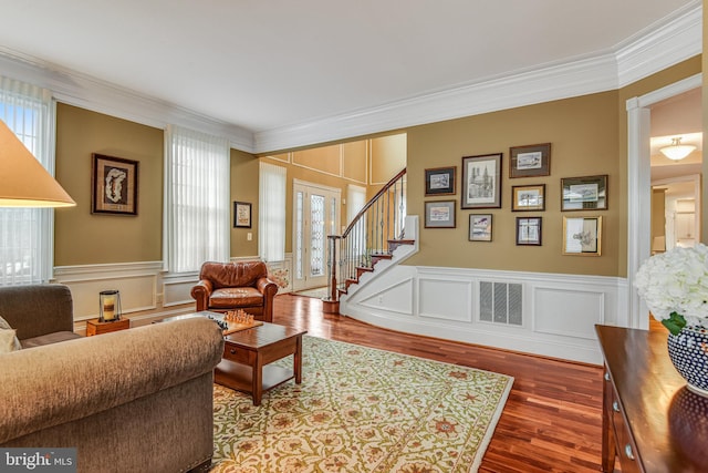 living area with stairway, a healthy amount of sunlight, and ornamental molding