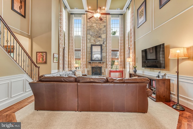 living room with a wainscoted wall, a fireplace, stairs, a towering ceiling, and a decorative wall