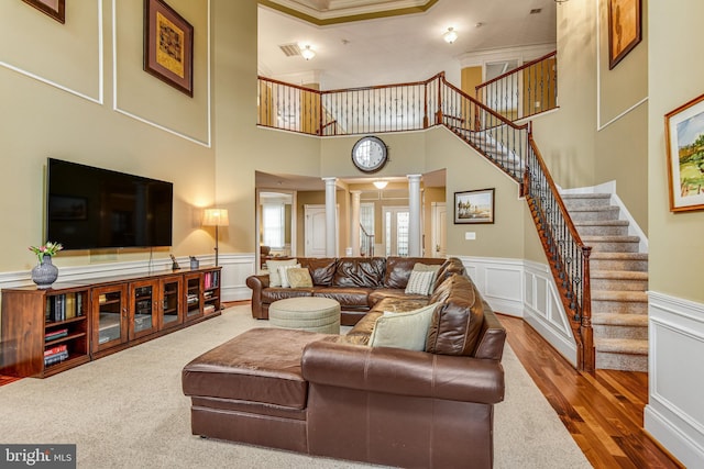 living room featuring decorative columns, wood finished floors, stairs, and a decorative wall