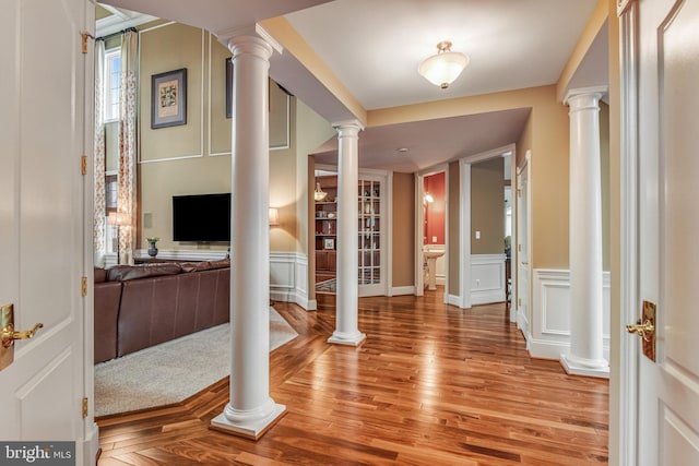 entrance foyer with a decorative wall, decorative columns, and light wood-style floors