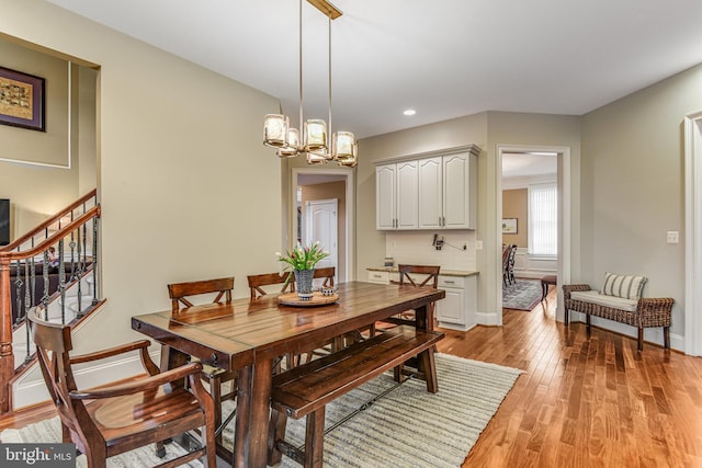 dining room featuring recessed lighting, stairway, an inviting chandelier, light wood finished floors, and baseboards