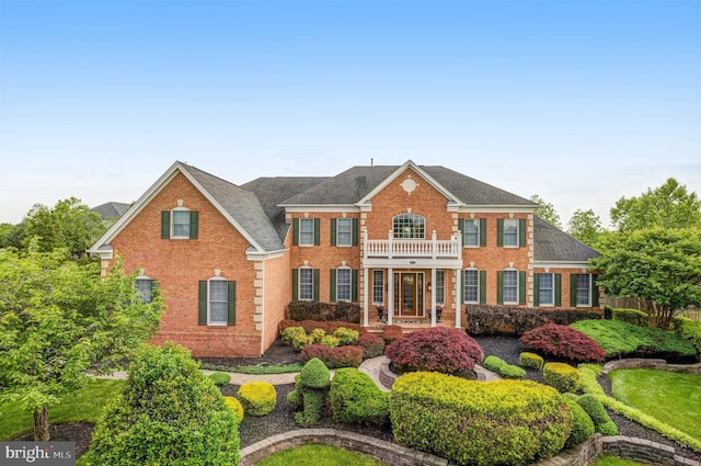 colonial-style house featuring brick siding and a balcony