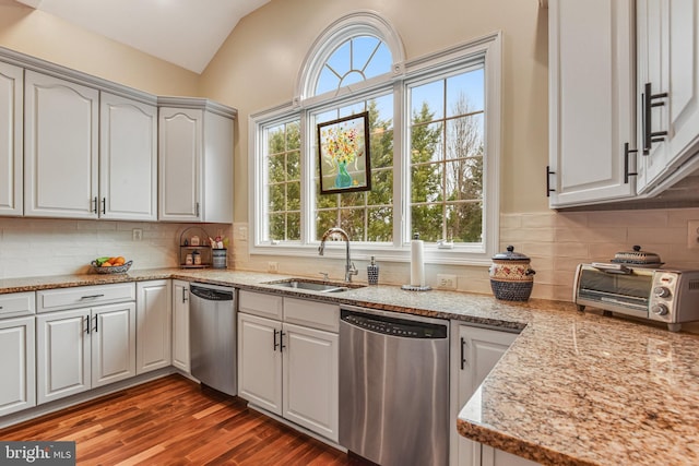 kitchen with dishwasher, vaulted ceiling, wood finished floors, and a sink