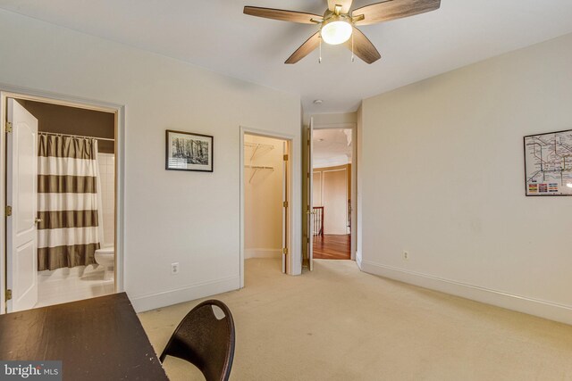 office area with light carpet, a ceiling fan, and baseboards