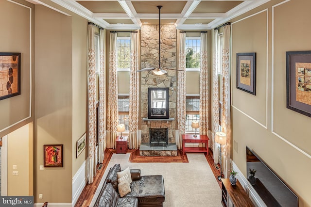 living room featuring a stone fireplace, beam ceiling, and coffered ceiling