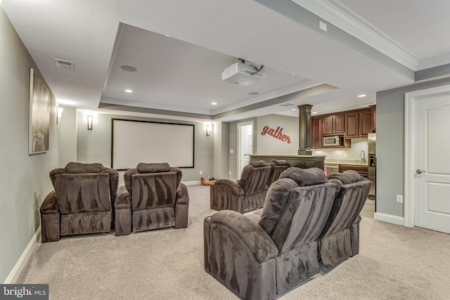 home theater featuring light carpet, visible vents, a tray ceiling, and ornamental molding