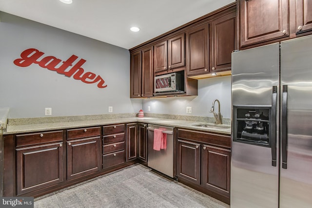 kitchen with light stone counters, recessed lighting, a sink, stainless steel appliances, and dark brown cabinets