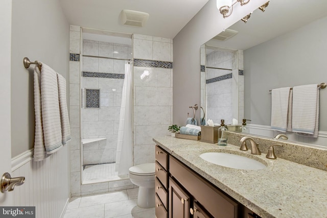 bathroom featuring vanity, toilet, tile patterned flooring, and a tile shower