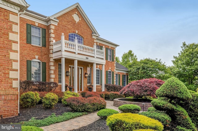 view of front of home with brick siding and a balcony