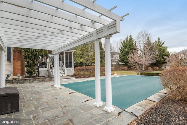 view of swimming pool featuring fence, a covered pool, a pergola, a sunroom, and a patio area