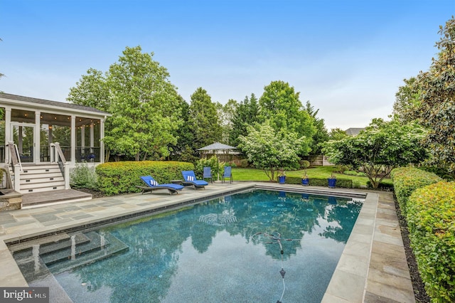 pool with a patio, fence, and a sunroom