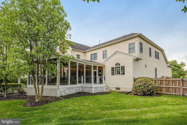 rear view of property featuring fence, a lawn, and a sunroom