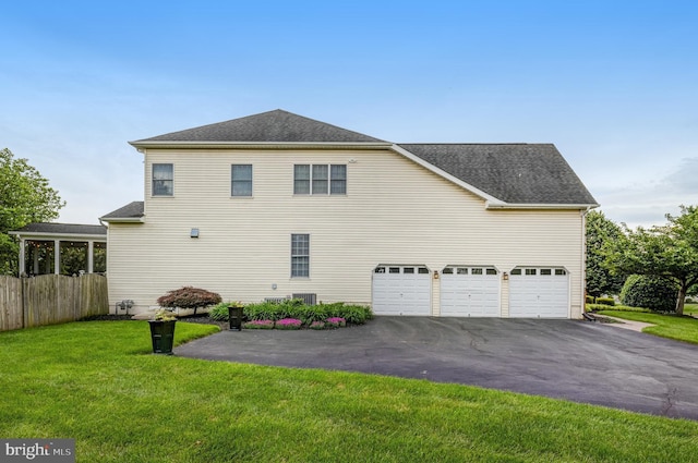 view of home's exterior with aphalt driveway, an attached garage, a lawn, and roof with shingles