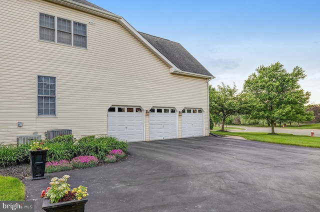 view of home's exterior featuring aphalt driveway, an attached garage, and roof with shingles