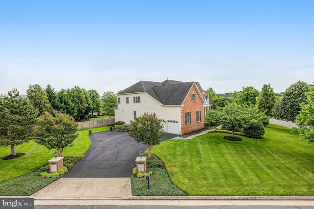 view of front of house featuring brick siding, a front lawn, fence, aphalt driveway, and a garage