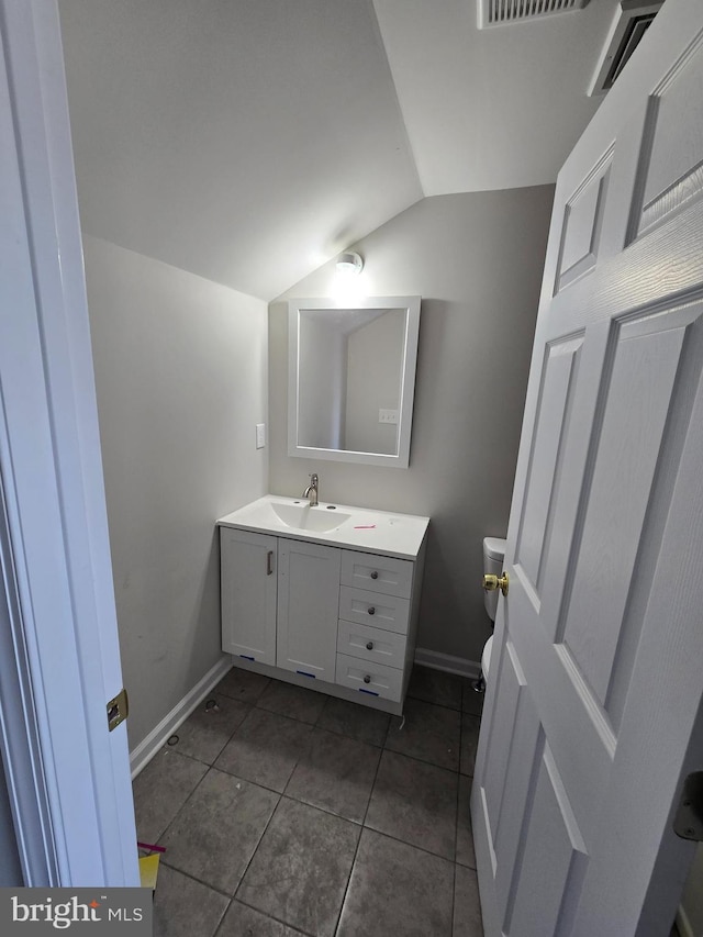 half bath with tile patterned flooring, toilet, vanity, baseboards, and vaulted ceiling