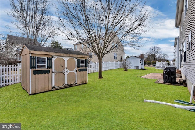 view of yard featuring a storage shed, a fenced backyard, and an outdoor structure