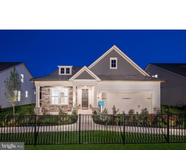 craftsman-style home featuring metal roof, a fenced front yard, an attached garage, stone siding, and a standing seam roof