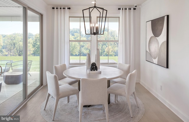 dining room with light wood-type flooring, an inviting chandelier, and baseboards