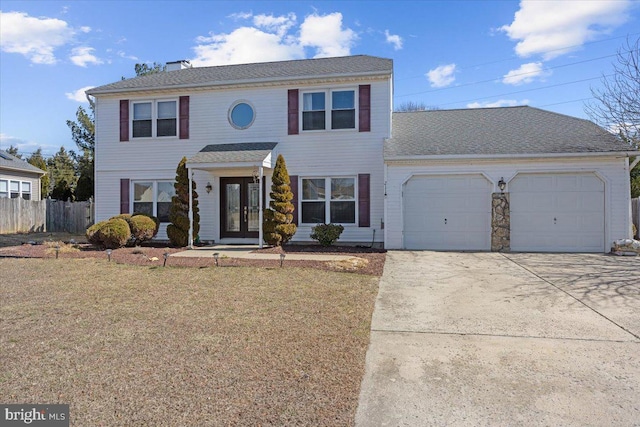 colonial inspired home featuring french doors, concrete driveway, a front yard, fence, and a garage