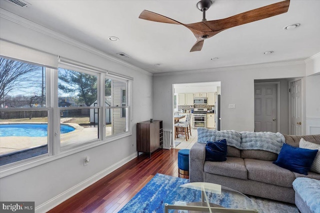 living room with dark wood-style flooring, visible vents, ornamental molding, ceiling fan, and baseboards