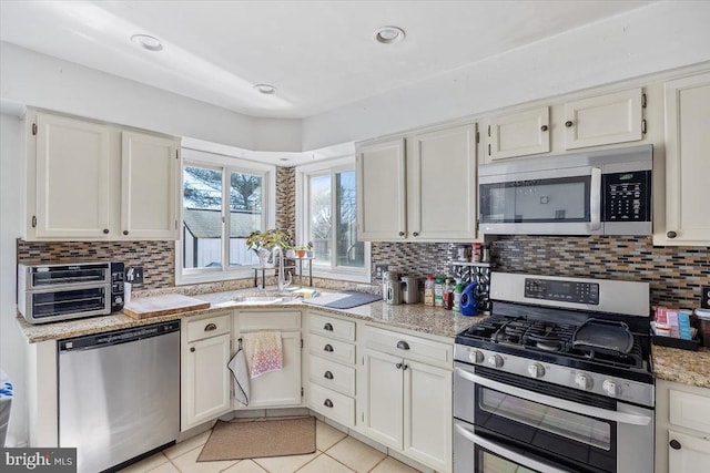 kitchen with stainless steel appliances, light tile patterned floors, and tasteful backsplash